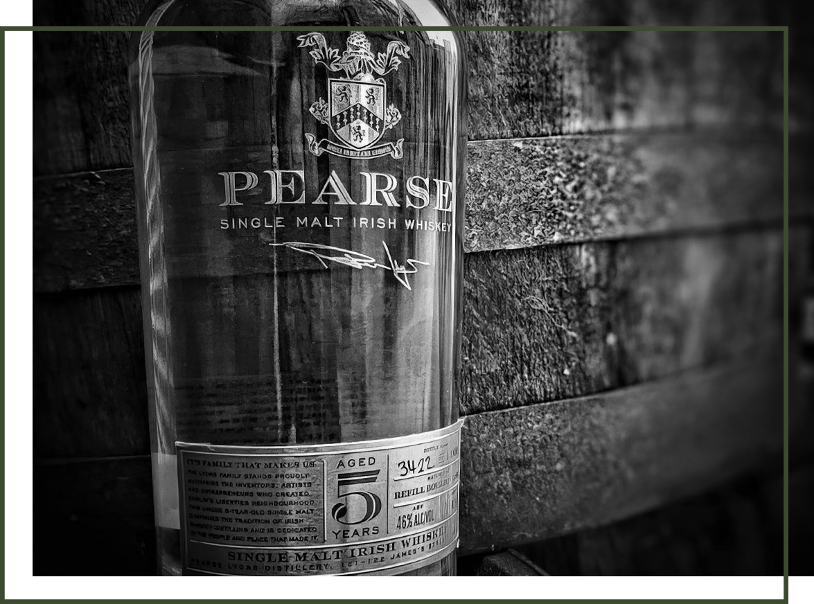 Pearse Lyons Irish Whiskey next to a weathered bourbon barrel